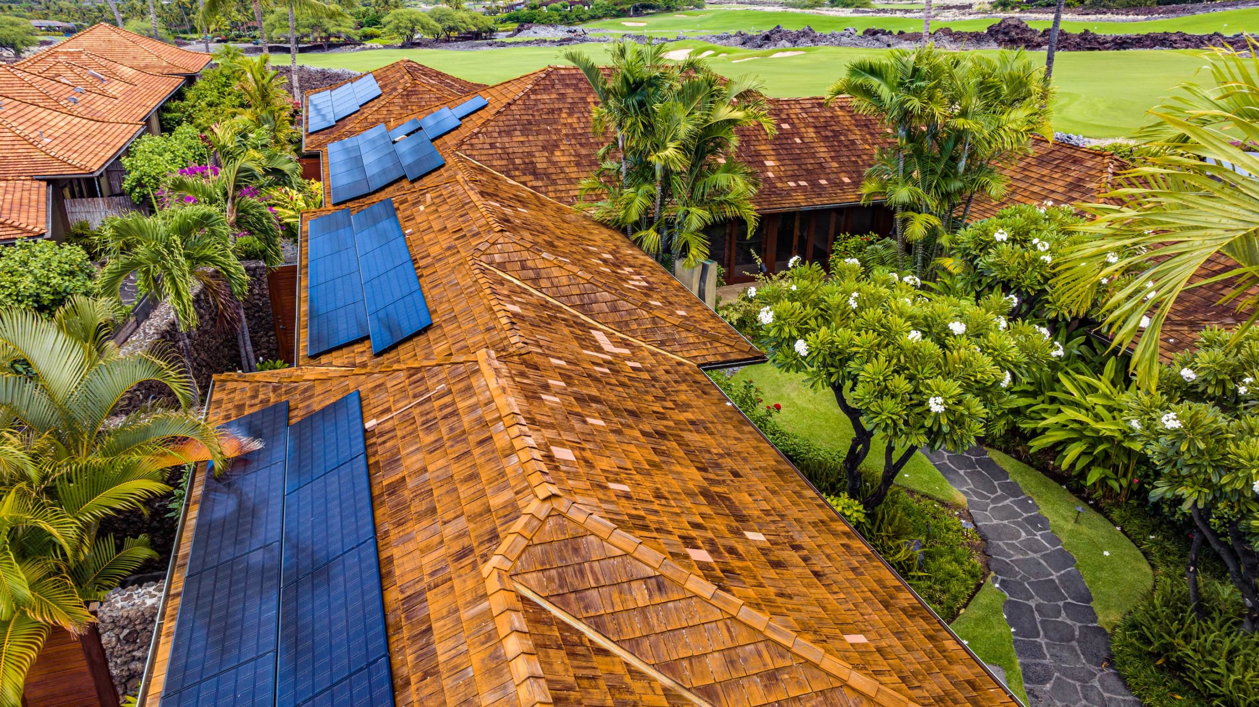 An aerial view of a house with solar panels on the roof.