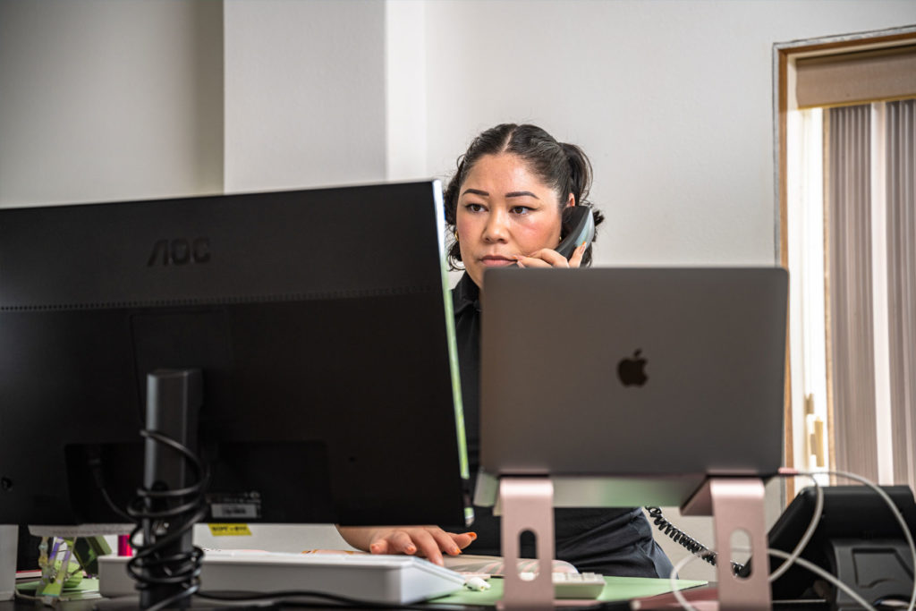 A woman talking on the phone in front of a computer.