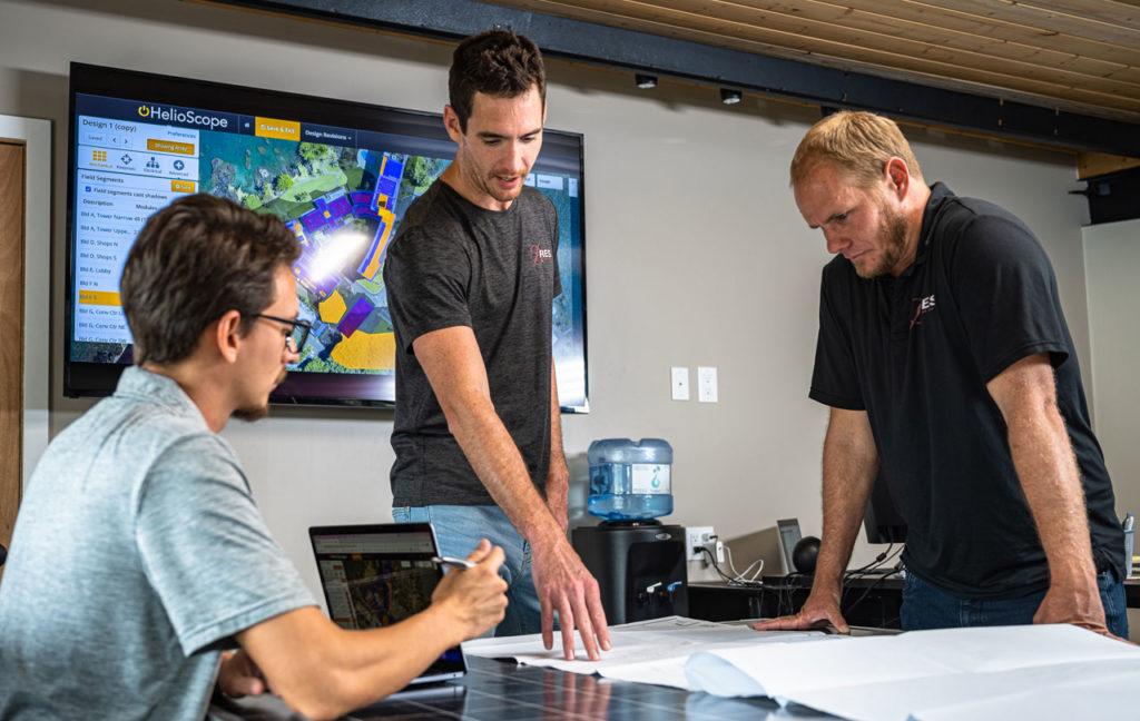 Three men standing around a table looking at a map.