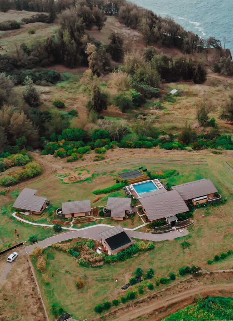 An aerial view of a multi-family residence with rooftop solar panels near the ocean. 