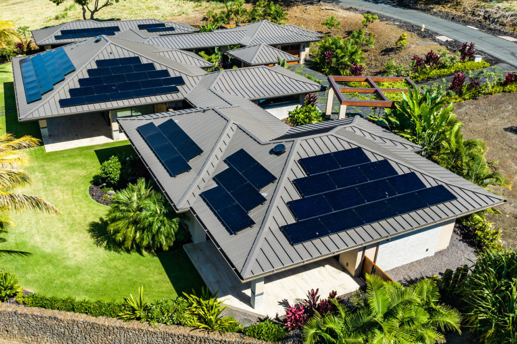 An aerial view of a home with solar panels on the roof.