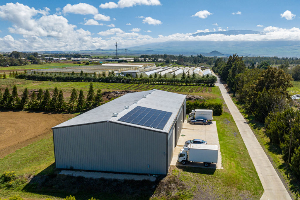 An aerial view of a warehouse with solar panels on the roof.