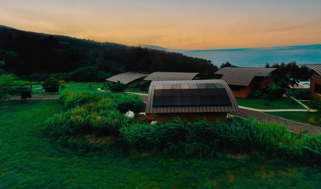 An aerial view of a multi-family home with solar panels on the roof and a view of the ocean.