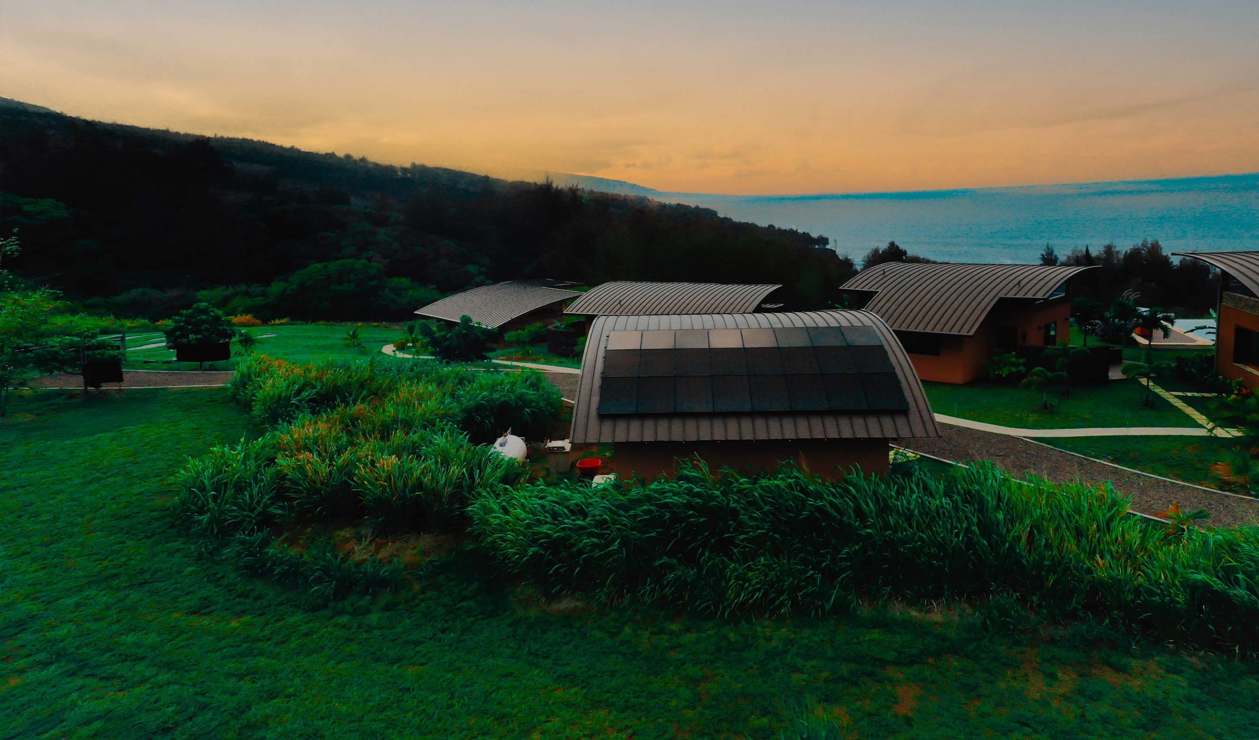 An aerial view of a multi-family home with solar panels on the roof and a view of the ocean.
