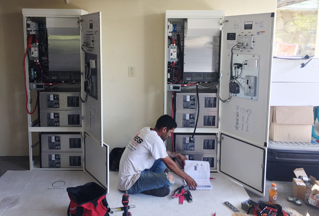 A man is working on electrical equipment in a room.